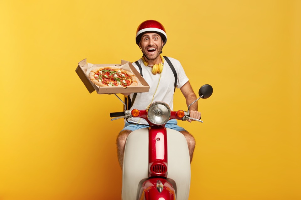 Livreur Wise Eat souriant avec une pizza sur son scooter